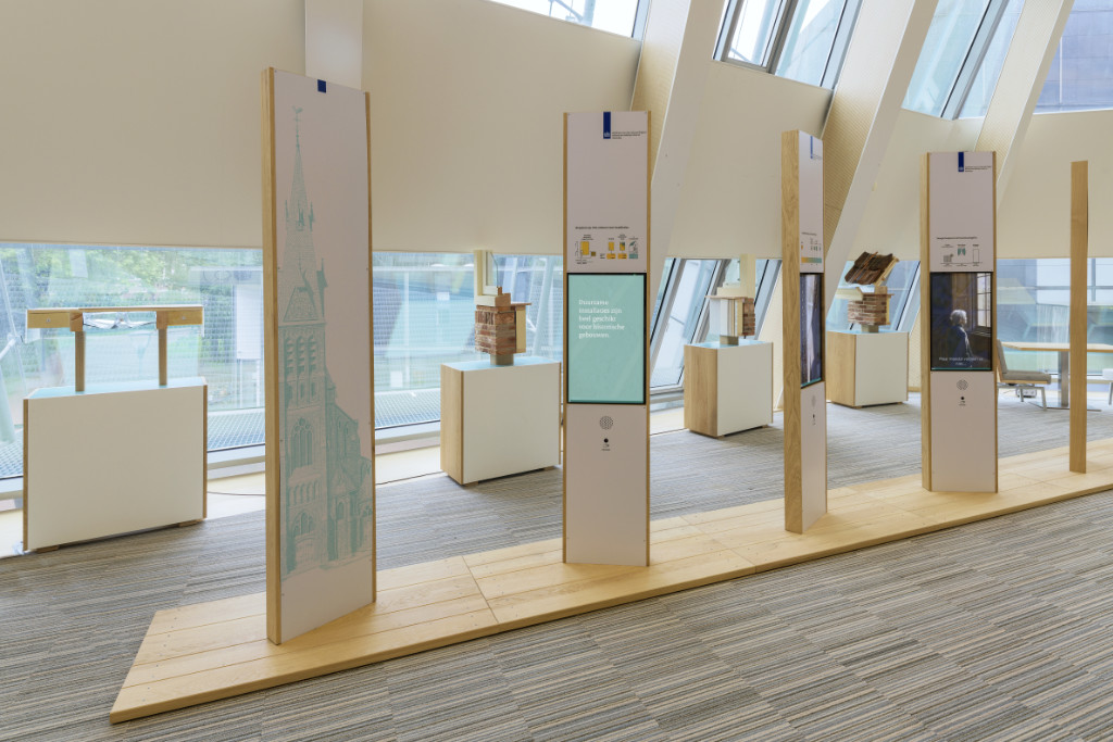 overzichtsfoto met zuilen met video en op de achtergrond de sokkels met bouwfragmenten.